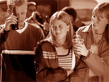 Two teens offering another teen alcohol